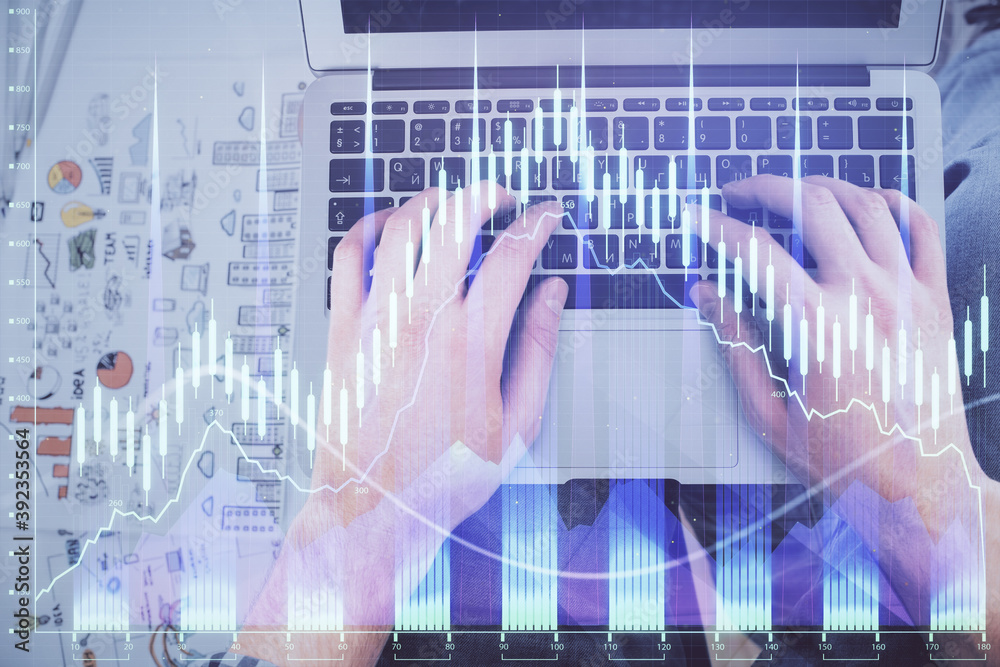 Double exposure of man's hands typing over laptop keyboard and forex chart hologram drawing. Top view. Financial markets concept.