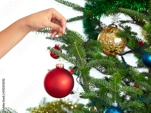 Woman holding Christmas ornament in a hand decorating a Christmas tree