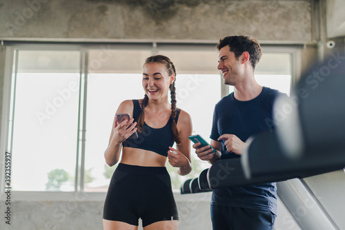 Couples exercise at the gym. Couple having fun playing with smartphones Near the exercise machine