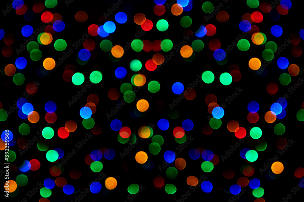 Defocused Christmas lights background, abstract texture with blurred multicolored circles of Christmas lights.