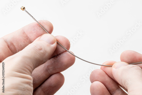 person holding new music string for electric guitar over white background. replacing string on a guitar