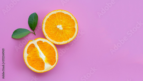 High vitamin C, Juicy and sweet. Fresh orange fruit with green leaves on pink background.