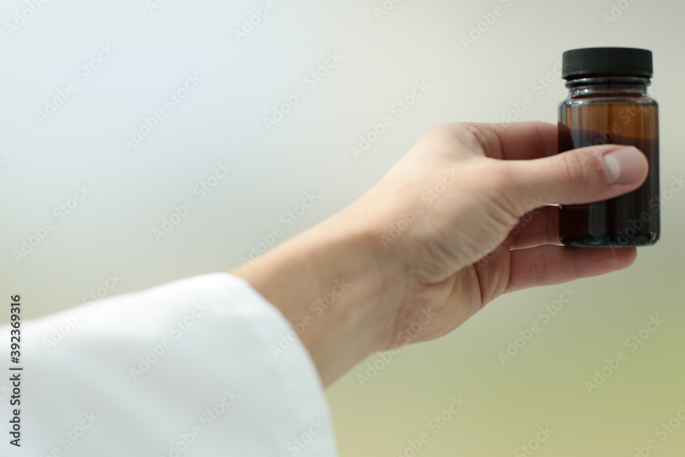 Doctor's hand holding a small medicine bottle Doctor's hand holding a small medicine bottle