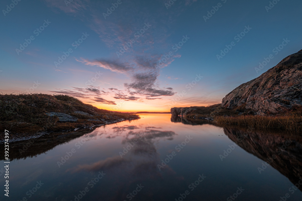 Gorgeous view of a calm lake surrounded by rocks, with the sky reflected on the water during sunset
