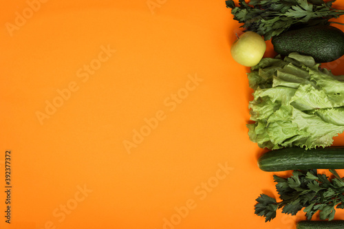 Greens and green vegetables on orange background, copy space. Vegetarian food