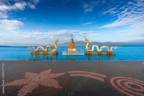 Naga statue with bright sky, clouds, mountains background and fresh water lake (Kwan Phayao, one of Phayao famous attractions.) in Phayao, Thailand (Thai Language translate “Happiness Phayao” ). photo