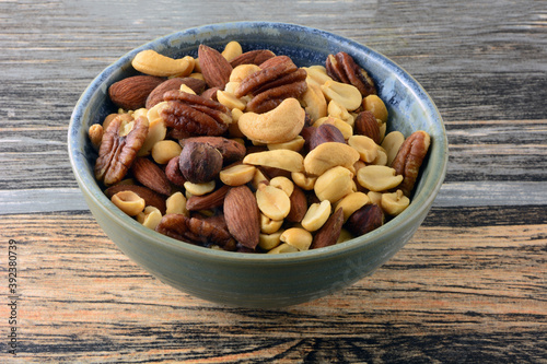 Mixed nuts with peanuts, almonds, cashews, hazelnuts and pecans in snack bowl on table
