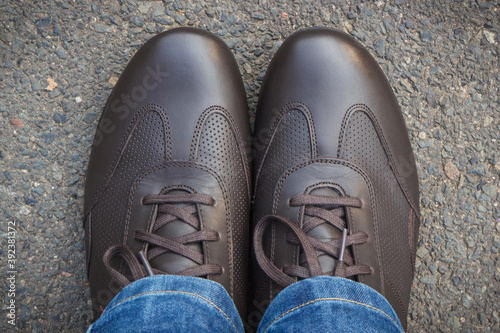 Comfortable brown leather shoes for men on asphalt road or footpath. Male footwear