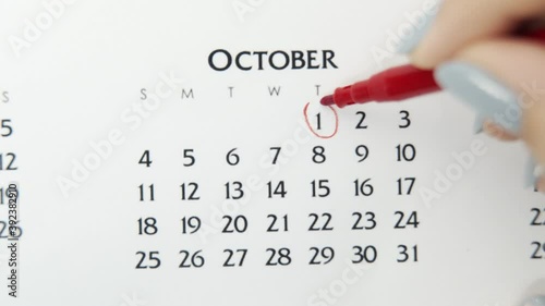 Female hand circle day in calendar date with a red marker. Business Basics Wall Calendar Planner and Organizer. October 1th