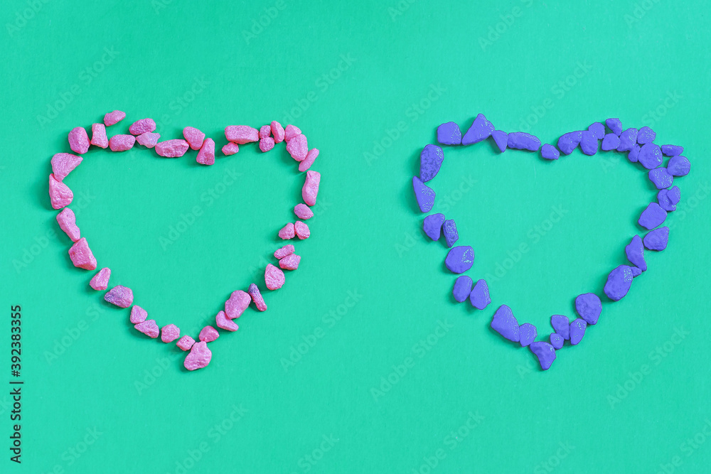 Two hearts made of decorative stones on a green background