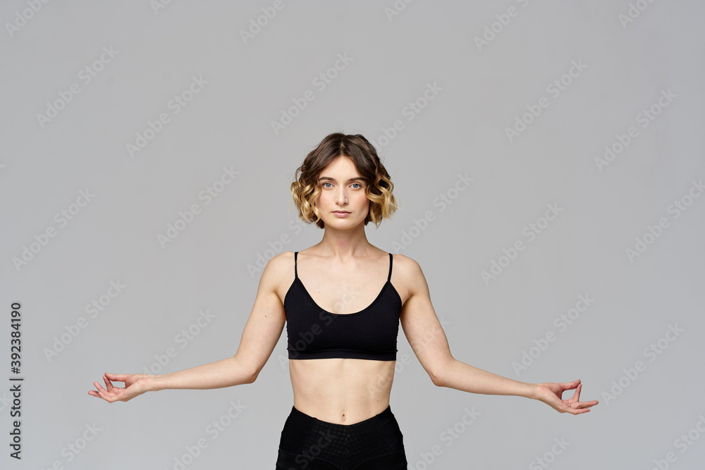 A slender woman is gesturing with her hands on a gray background Sport Fitness figure A slender woman is gesturing with her hands on a gray background Sport Fitness figure