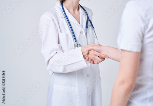 Doctor and patient shake hands with each other on a light background cropped view