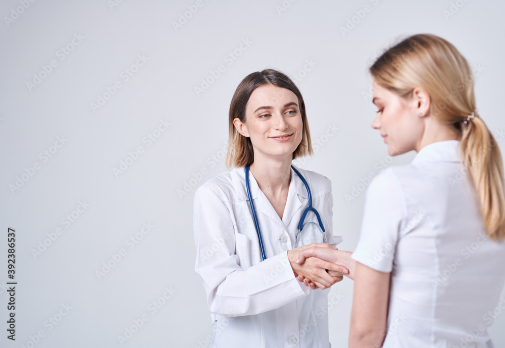 Happy woman doctor in medical gown with stethoscope and patient back view Happy woman doctor in medical gown with stethoscope and patient back view