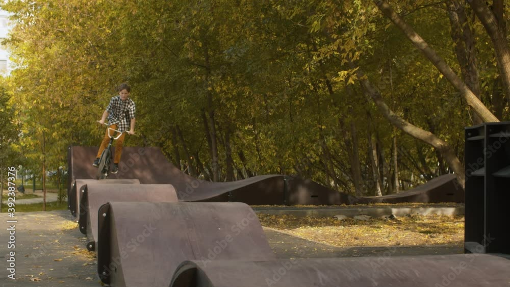 Young boy, biker riding on the pump track in the park at sunny day. Childrens sport and healthy lifestyle concept Young boy, biker riding on the pump track in the park at sunny day. Childrens sport and healthy lifestyle concept