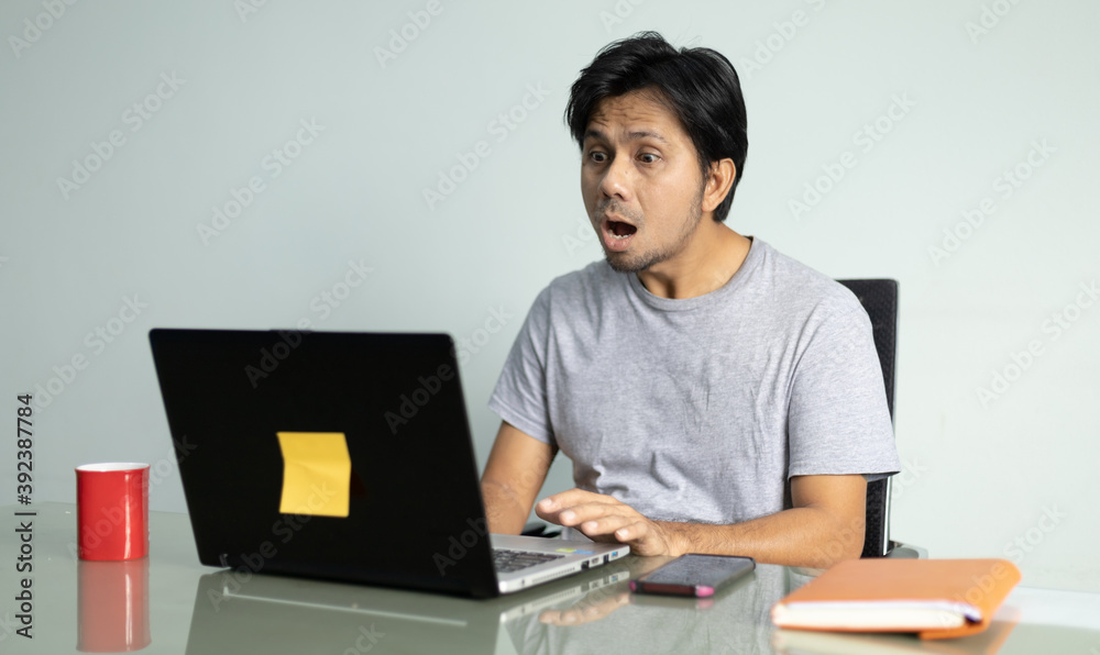 young asian man looking at laptop screen shocked young asian man looking at laptop screen shocked