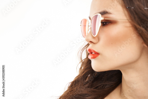 Portrait of brunette woman in sunglasses naked shoulders light background