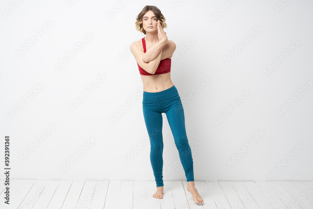 sports woman in a bright room doing yoga in full growth blue leggings and a red tank top sports woman in a bright room doing yoga in full growth blue leggings and a red tank top