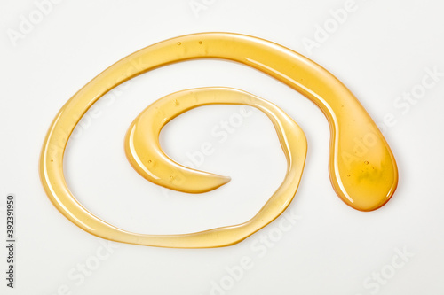Decorative spiral of golden honey on white