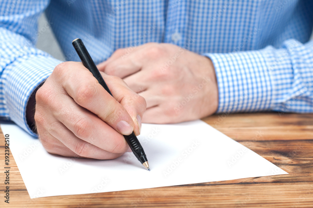 The hand writes on a blank sheet of paper. Businessman at the table. The hand writes on a blank sheet of paper. Businessman at the table.