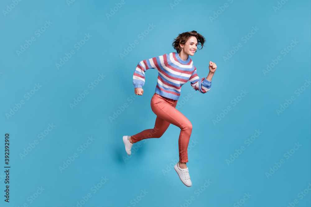 Full length body size side profile photo of jumping high running fast girl smiling isolated on vibrant blue color background