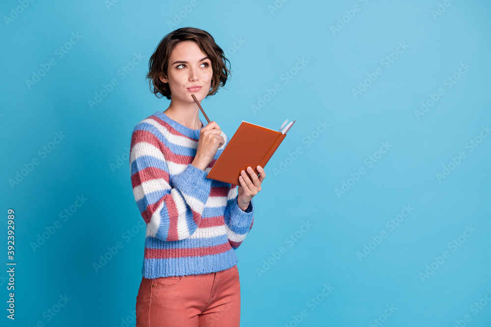 Photo portrait of thoughtful girl keeping pen notebook thinking about idea plan isolated on bright blue color background Photo portrait of thoughtful girl keeping pen notebook thinking about idea plan isolated on bright blue color background