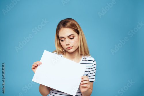 Emotional woman holding a sheet of paper in her hands lifestyle close-up blue background Copy Space