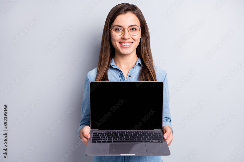 Photo of optimistic cute long hairdo lady show laptop wear spectacles blue shirt isolated on grey color background Photo of optimistic cute long hairdo lady show laptop wear spectacles blue shirt isolated on grey color background