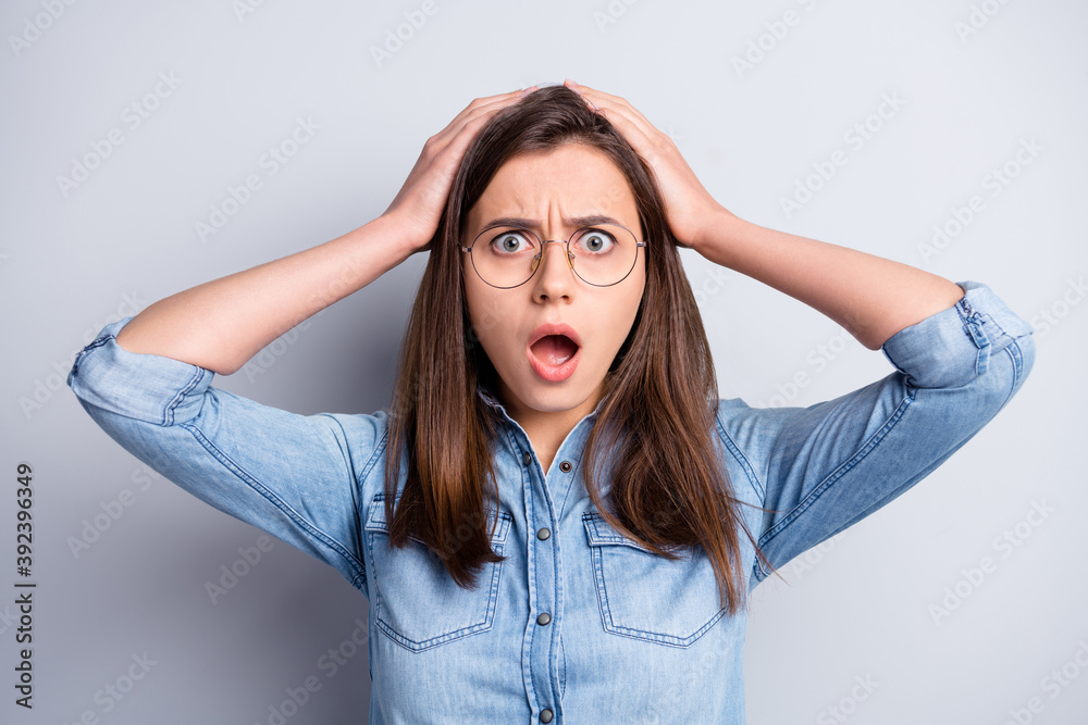 Photo of impressed pretty young woman wear jeans shirt spectacles arms head isolated grey color background Photo of impressed pretty young woman wear jeans shirt spectacles arms head isolated grey color background