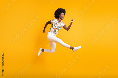 Full size profile side photo of young african attractive crazy smiling girl woman female jump fly isolated on yellow color background
