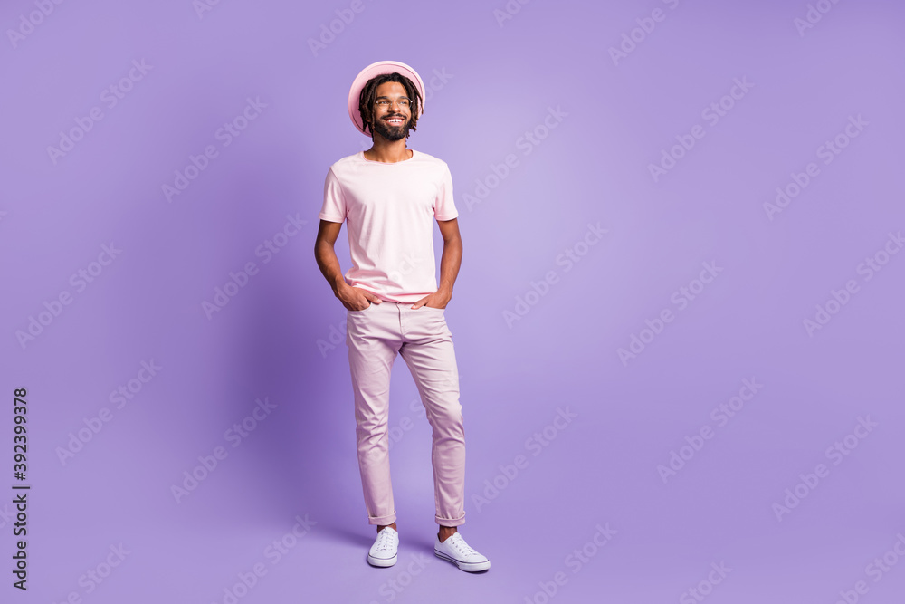 Full size photo of young african handsome smiling positive man look copyspace hold hands in pockets isolated on purple color background Full size photo of young african handsome smiling positive man look copyspace hold hands in pockets isolated on purple color background