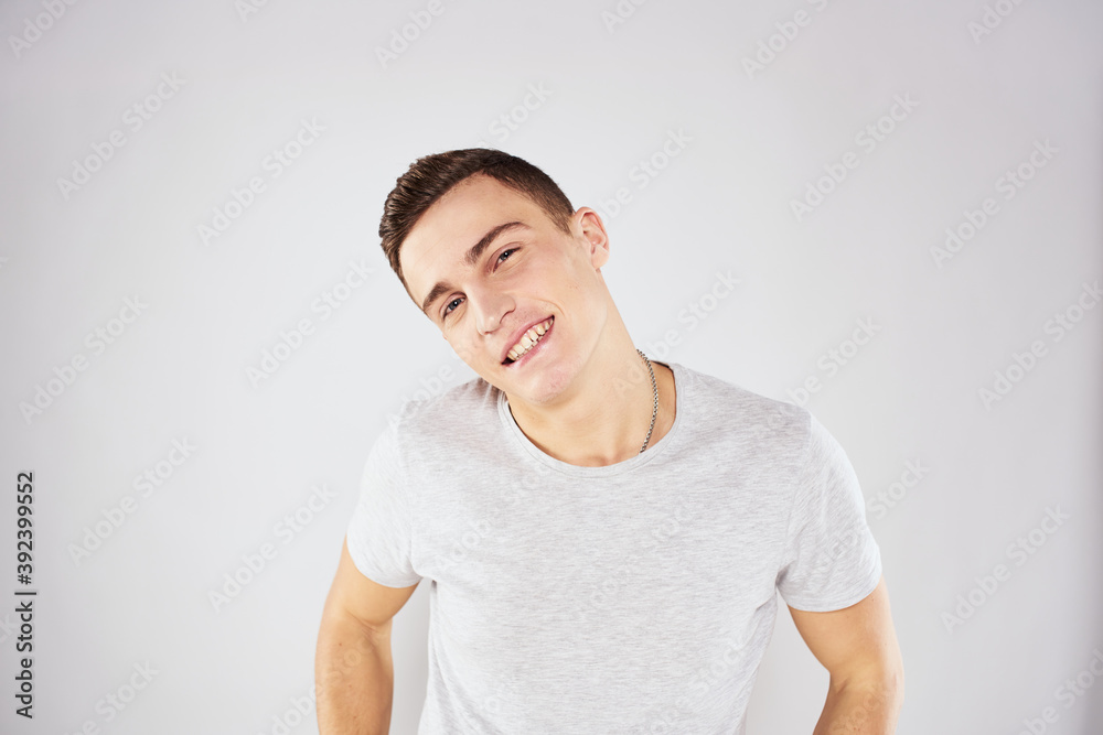 Man in a white t-shirt emotions gestures with hands close-up cropped view light background Man in a white t-shirt emotions gestures with hands close-up cropped view light background
