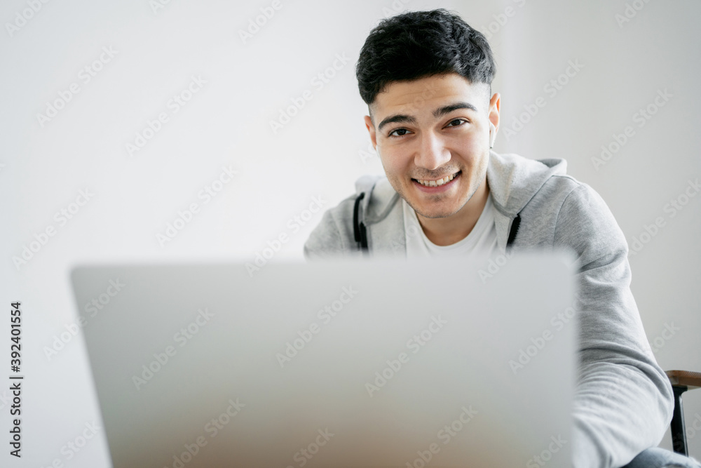 talks with friends online in a convenient social community. Sitting on the couch in the hands of a gadget. Looking at the camera, a dark-haired man smiles and enjoys communicating with loved ones. talks with friends online in a convenient social community. Sitting on the couch in the hands of a gadget. Looking at the camera, a dark-haired man smiles and enjoys communicating with loved ones.