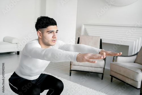 home training in stylish sportswear hardy athletic man doing plank exercises doing sports fitness. Healthy lifestyle a young man is quarantined in an apartment. photo