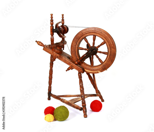 Slika na platnu Closeup shot of an old wooden spinning wheel with balls of yarn isolated on whit