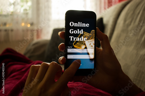 Close up of woman lying in bed under warm blanket with smartphone. Online gold trade concept photo