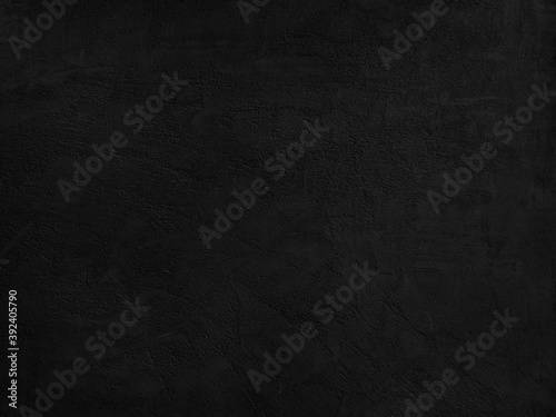 Black stone background. Decorative plaster on a concrete wall. Dark rough texture background.