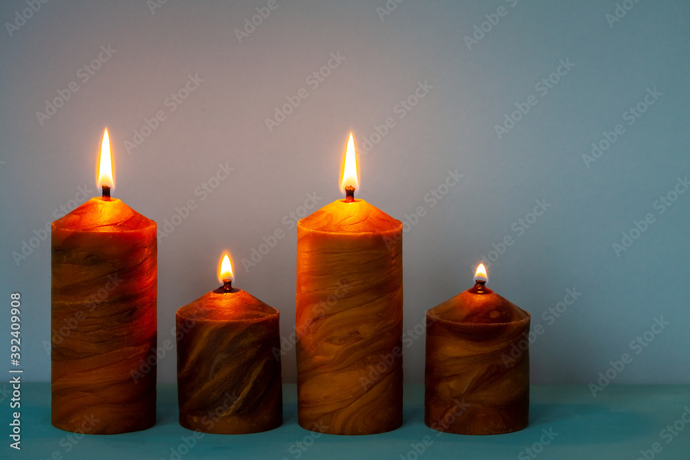 Four natural beeswax candles on bright blue background. Decoration with copy space. Four natural beeswax candles on bright blue background. Decoration with copy space.