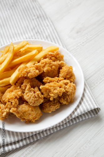 Homemade Fried Chicken Bites and French Fries on a plate, side view. Copy space.