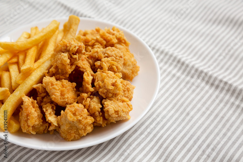 Homemade Fried Chicken Bites and French Fries on a plate, side view. Copy space.