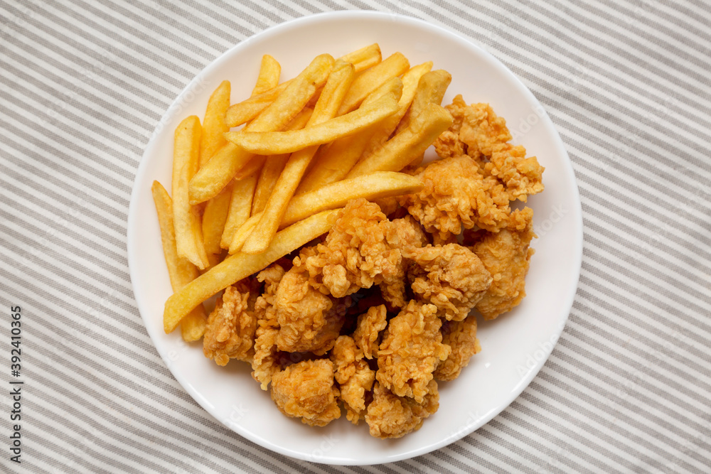 Homemade Fried Chicken Bites and French Fries on a plate on cloth, overhead view. Flat lay, top view, from above. Close-up. Homemade Fried Chicken Bites and French Fries on a plate on cloth, overhead view. Flat lay, top view, from above. Close-up.