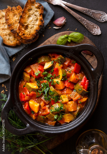 Cooked various chopped vegetables with herbs in a black cooking pot