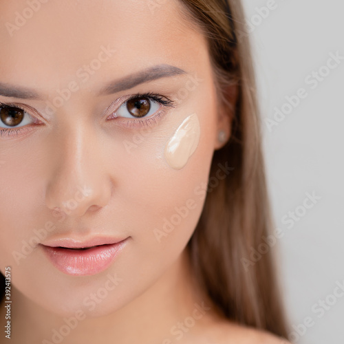 Foundation on the cheek, portrait of a young beautiful woman with beautiful clear skin.