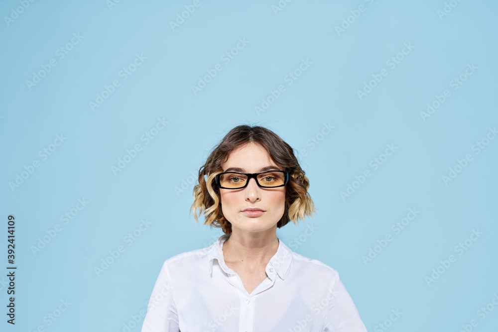 Business woman on a blue background glasses with dark rims curly hair Light shirt cropped view Business woman on a blue background glasses with dark rims curly hair Light shirt cropped view