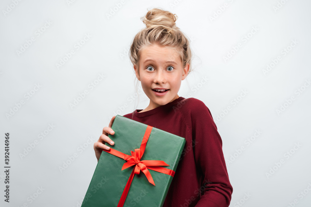 Portrait of happy blonde girl holding gift decorated with ribbon. Studio shot white background Portrait of happy blonde girl holding gift decorated with ribbon. Studio shot white background