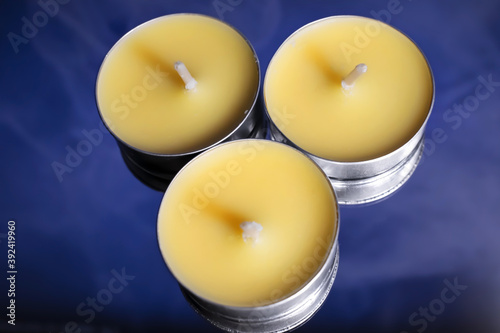 Three yellow candles stand on a blue background. photo