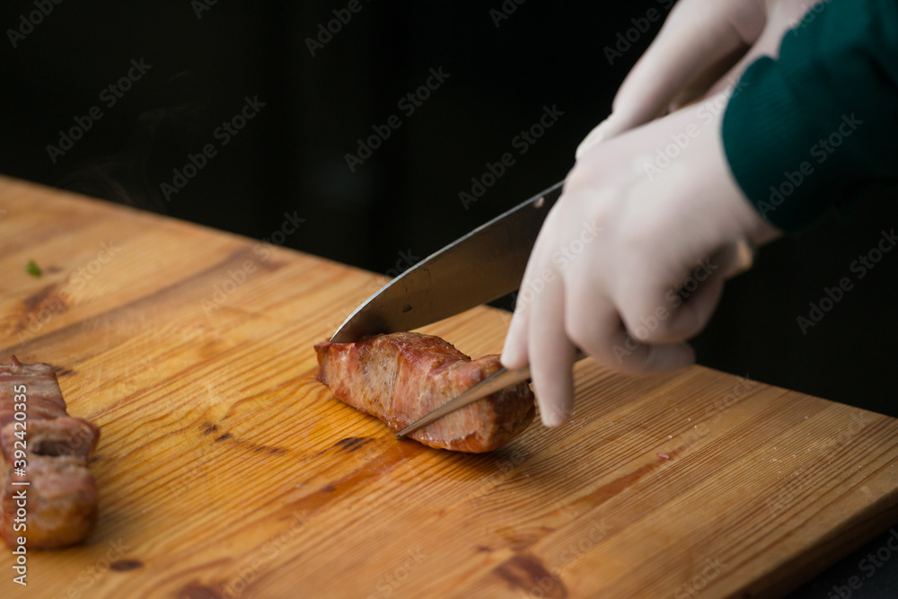 Closeup of chief cutting delicious roasted pork meat wrapped in bacon. Irish traditional dish wrapped pork loin with roasted garlic