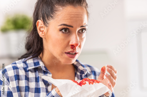 Woman find out her nose is bleeding after sneezing into a tissue photo