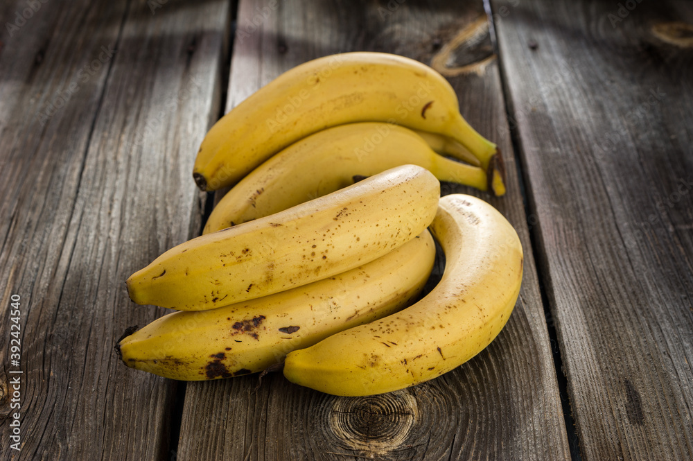 a bunch of ripe yellow bananas on a dark wooden background a bunch of ripe yellow bananas on a dark wooden background