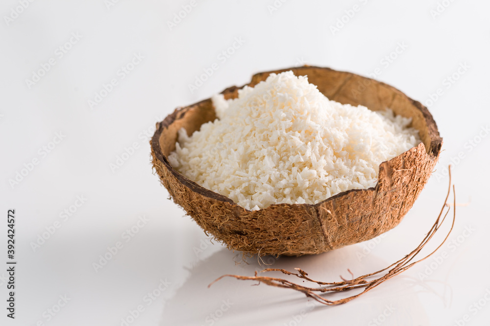 Coconut flakes in coconut shell on white background side view Coconut flakes in coconut shell on white background side view