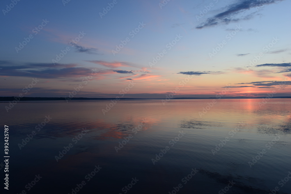 Twilight glow in the clear sky on the horizon above the calm water surface
